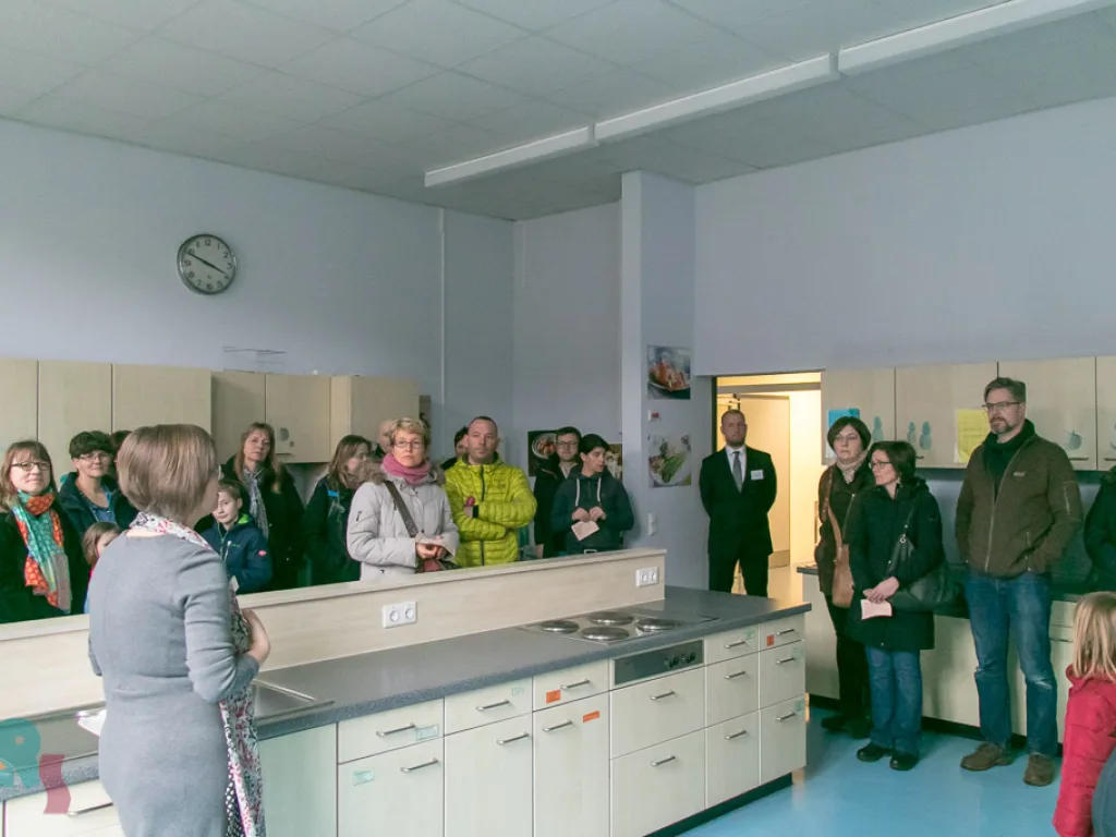 Besucher stehen in der Schulküche und hören zu.